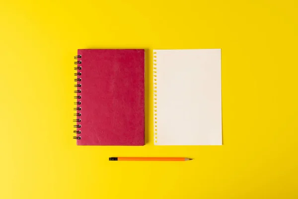 Composition of notebooks with copy space and pencil on yellow surface. School equipment, tools, education and creativity concept.