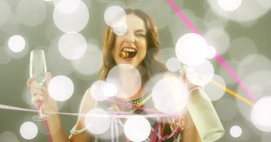 Animation of dots over happy caucasian woman with glass of wine dancing. Party, fun and celebration concept digitally generated video.