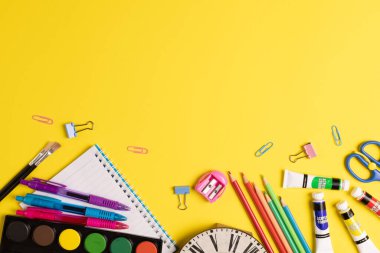 Çeşitli ofis malzemelerini düşünün. Plastik çatal bıçak, boya, sarı arka planda boya kalemleri. Eğitim, öğrenme ve yaratıcılık.