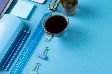 Çeşitli ofis malzemelerinin resmi, mavi arka planda kağıt ve bir fincan koyu kahve. Eğitim, öğrenme ve yaratıcılık.