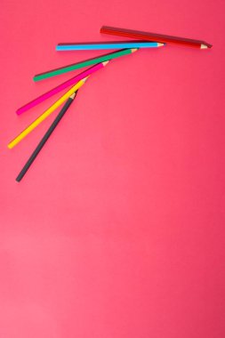Composition of colorful crayons on pink surface with copy space. School equipment, drawing tools and creativity concept.