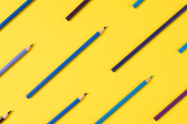 Sarı arka planda mavinin farklı tonlarında boya kalemleri hayal edin. Eğitim, öğrenme ve yaratıcılık.