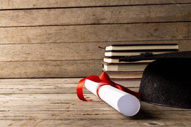 Image of stack of books and diploma on wooden surface. School equipment, tools, learning and education concept.
