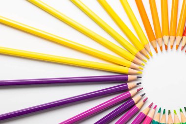 Beyaz yüzeydeki renkli pastel boyaların merkezi bileşimi. Okul ekipmanları, çizim araçları, şablon ve yaratıcılık kavramı.