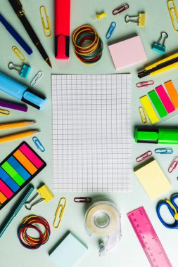 Kontrol kağıdının dikey bileşimi ve yeşil yüzeydeki okul araçlarından yapılmış çerçeve. Okul ekipmanları, araçlar ve yaratıcılık kavramı.