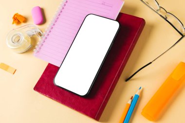 Fotokopi alanı olan akıllı telefon, not defterleri, gözlükler ve sarı yüzey üzerindeki okul aletlerinin bileşimi. Okul ekipmanları, araçlar, teknoloji ve yaratıcılık kavramı ile öğrenme.