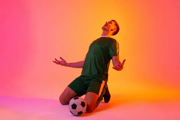 Šťastný Kavkazský Fotbalista Zvedající Ruce Fotbalem Nad Neonově Růžovým Osvětlením — Stock fotografie