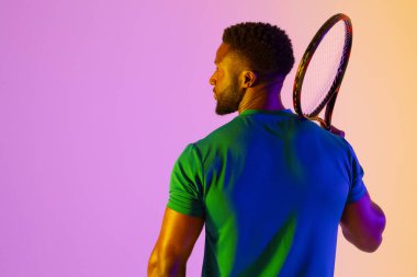 Afrika kökenli Amerikalı erkek tenisçinin menekşe ve sarı neon ışıklı görüntüsü. Spor, hareket, fitness ve aktif yaşam tarzı konsepti.