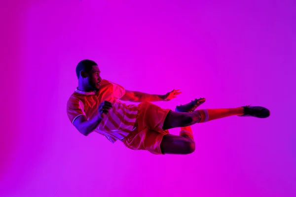 African American Male Soccer Player Jumping Neon Pink Lighting Sport — Stockfoto