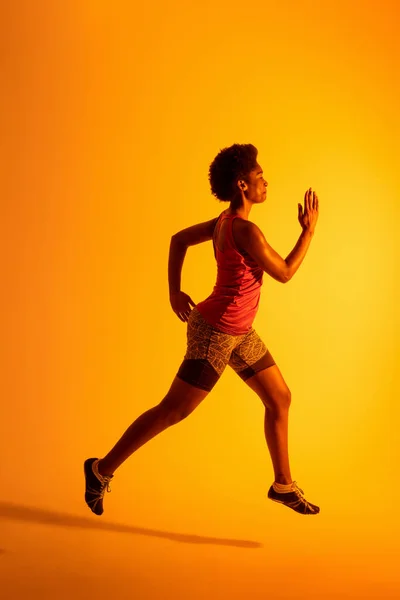 Vertical Image African American Female Athlete Running Neon Orange Lighting —  Fotos de Stock