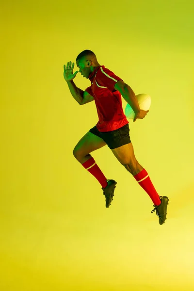 African American Male Rugby Player Running Rugby Ball Yellow Lighting — Fotografia de Stock