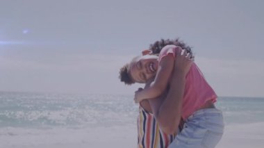 Afrika kökenli Amerikalı kadın ve kızının kumsalda kucaklaşmasının animasyonu. Yaşam tarzı, aile ve ışık konsepti dijital olarak oluşturulmuş video.