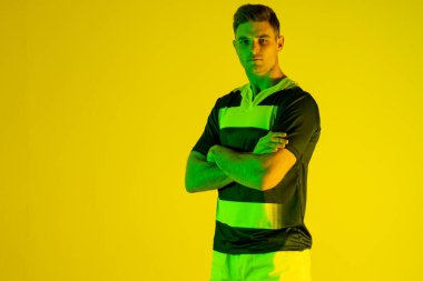 Kafkas erkek rugby oyuncusunun portresi. Kolları turuncu ışıkta çaprazlanmış. Spor, hareket, eğitim ve aktif yaşam tarzı kavramı.