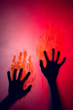 Composition of shape of black hands with blood stains on red background. Halloween tradition and celebration concept.