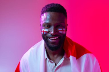 Image of happy african american male soccer fan with flag of england in neon pink lighting. Sport, fans, cheering and emotions concept.