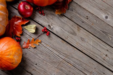 Composition of pumpkins and autumn leaves on wooden background. Halloween, autumn, tradition and celebration concept.