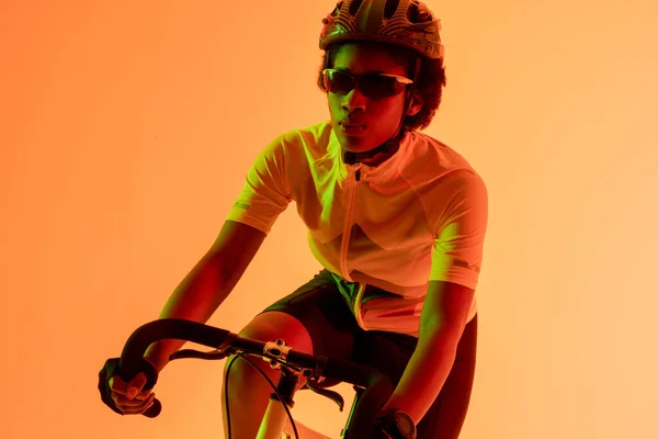 Εικόνα Ενός Αφροαμερικανού Ποδηλάτη Ποδήλατο Νέον Πορτοκαλί Φωτισμό Αθλητισμός Κίνηση — Φωτογραφία Αρχείου