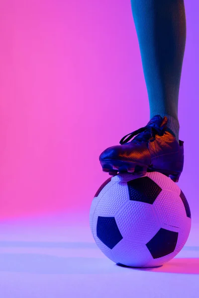 Male soccer player with football over neon pink lighting. Sport, movement, training and active lifestyle concept.
