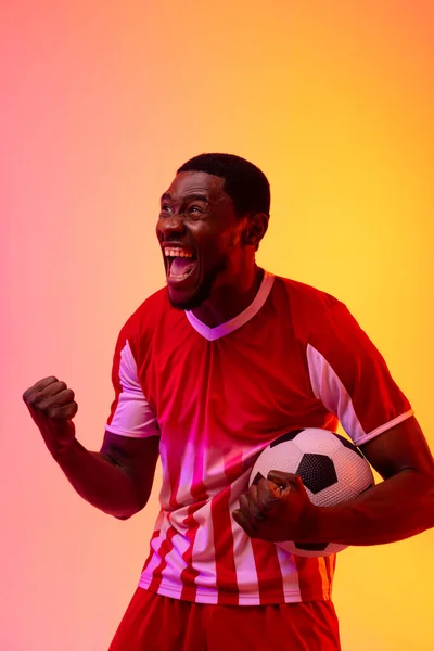 Счастливый Африканский Американский Футболист Футболом Над Неоновым Розовым Освещением Спорт — стоковое фото