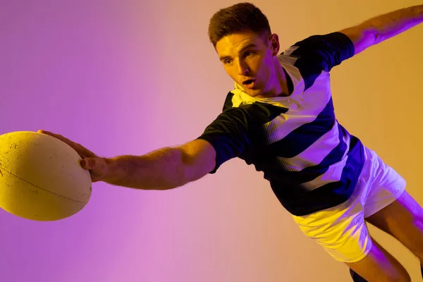 Caucasian Male Rugby Player Jumping Rugby Ball Pink Lighting Sport — 스톡 사진