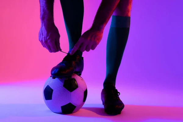 Caucasian Male Soccer Player Football Tying Shoes Neon Pink Lighting — Stok fotoğraf