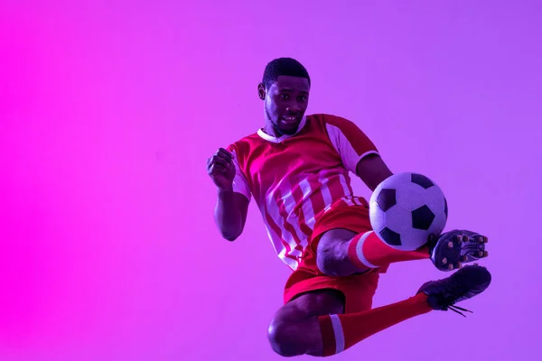 Afro Americano Jogador Futebol Masculino Chutando Futebol Sobre Iluminação Rosa — Fotografia de Stock