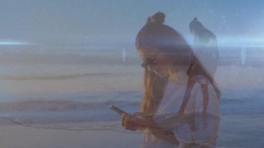 Sahilde akıllı telefon kullanan melez kadının üzerindeki ışık izlerinin animasyonu. Yaşam tarzı, aile ve ışık konsepti dijital olarak oluşturulmuş video.