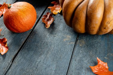 Composition of pumpkins and autumn leaves on wooden background. Halloween, autumn, tradition and celebration concept.