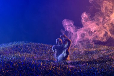 Siyah arka plan dumanlı çimenden el kaldırma kompozisyonu. Cadılar Bayramı geleneği ve kutlama konsepti.