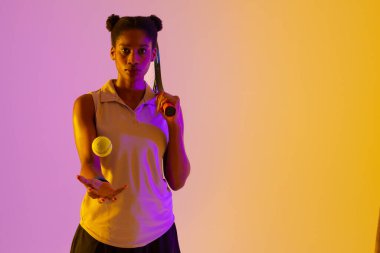 Afro-Amerikan bayan tenis oyuncusu neon menekşe ve sarı ışıklandırma. Spor, hareket, fitness ve aktif yaşam tarzı konsepti.