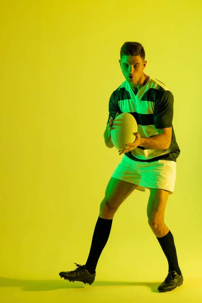 Caucasian Male Rugby Player Catching Rugby Ball Yellow Lighting Sport — 图库照片