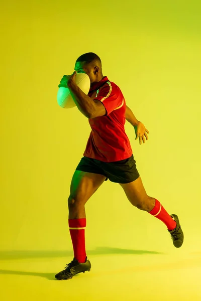 African American Male Rugby Player Running Rugby Ball Yellow Lighting — 图库照片