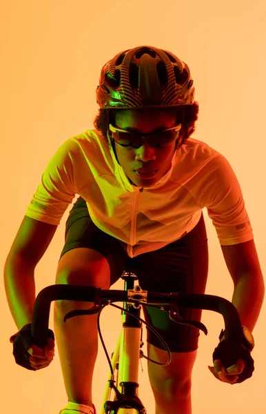 Κάθετη Εικόνα Του Αφροαμερικανού Ποδηλάτη Ιππασία Ποδήλατο Πορτοκαλί Φωτισμό Αθλητισμός — Φωτογραφία Αρχείου