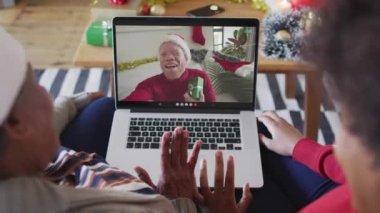 Animation of stay at home text over albino african american man having video call with family. Global pandemic and digital interface concept digitally generated video.