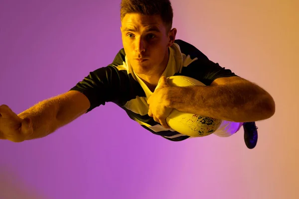 Caucasian Male Rugby Player Jumping Rugby Ball Pink Lighting Sport — Φωτογραφία Αρχείου