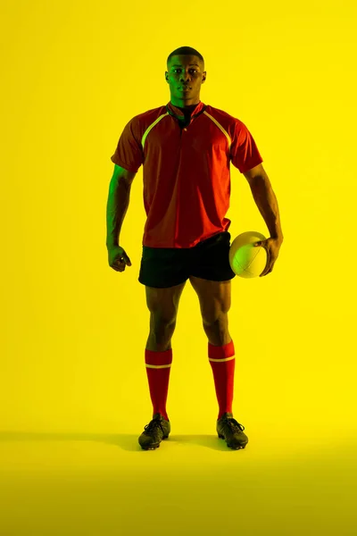 Портрет Африканского Американского Игрока Регби Мячом Регби Над Жёлтым Освещением — стоковое фото