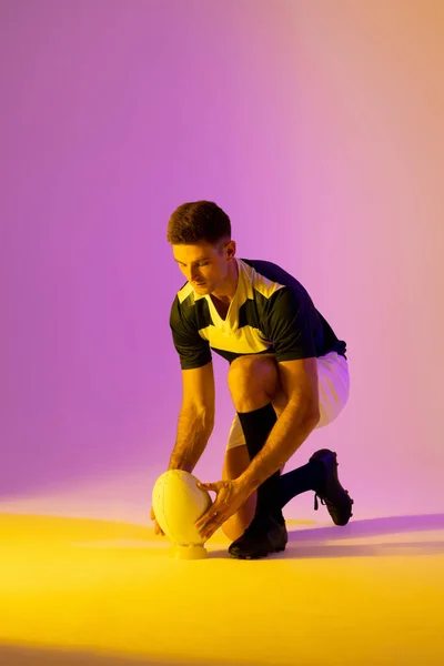 Белый Игрок Регби Приседающий Мячом Регби Над Розовым Освещением Спорт — стоковое фото
