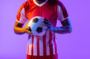 Neon pembe ışıkta futbol oynayan Afrikalı Amerikalı erkek futbolcu. Spor, hareket, eğitim ve aktif yaşam tarzı kavramı.