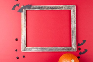 Fotokopi alanı olan çerçeve, cadılar bayramı süslemeleri ve kırmızı arka planda balkabağı bileşimi. Cadılar Bayramı, sonbahar, gelenek ve kutlama konsepti.