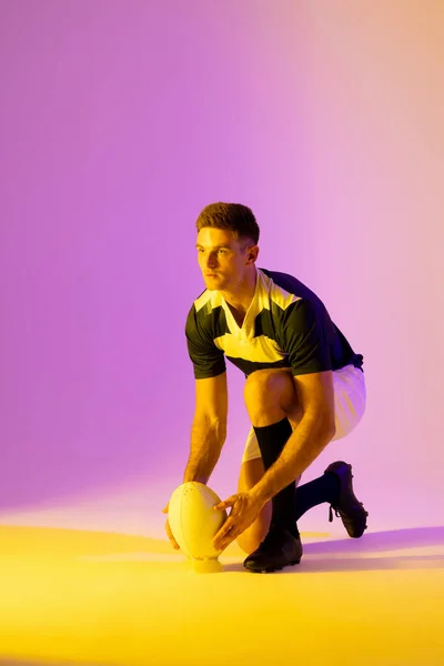 Caucasian Male Rugby Player Crouching Rugby Ball Pink Lighting Sport — Stock fotografie