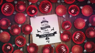 Kar animasyonu ve mutlu noel kartı ahşap yüzeyde kırmızı mücevherler üzerinde. Noel, kış ve gelenek konsepti dijital olarak oluşturulmuş video.