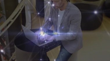Glowing network of connections over thoughtful caucasian businessman using a laptop at office. Global networking and business technology concept