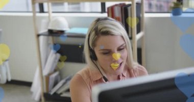 Telefon kulaklığı kullanan beyaz iş kadınının üzerinde sarı ve mavi kalplerin animasyonu. Ukrayna krizi, sosyal medya, iletişim, iş ve veri işleme kavramı dijital olarak oluşturulmuş video.