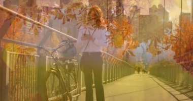 Animation of autumn leaves falling over caucasian man with bike using smartphone. Fall, seasons and passing concept digitally generated video.