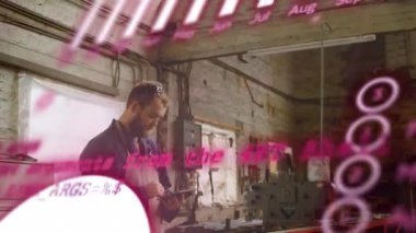 Animation of graphs over caucasian male engineer using smartphone in workshop. Small business, finance and economy concept digitally generated video.