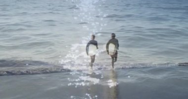 Deniz manzarası üzerinde sörf tahtası olan mutlu Afro-Amerikan çifti üzerine ışık yansıması. Tatiller, tatiller ve rahatlama konsepti dijital olarak oluşturulmuş video.