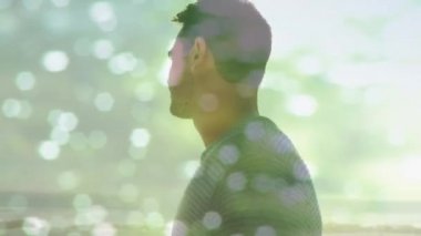 Animation of light reflection over happy caucasian man on beach. Holidays, vacations and relax concept digitally generated video.