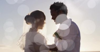 Animation of dots over happy african american newly married couple on beach. Holidays, vacations love, marriage concept digitally generated video.