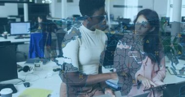 Animation of world map and icons over diverse female coworkers working in office. Business, finance, economy and technology concept digitally generated video.