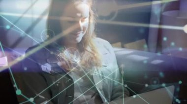 Animation of network of connections floating over caucasian woman using laptop at home. Global networking and business technology concept